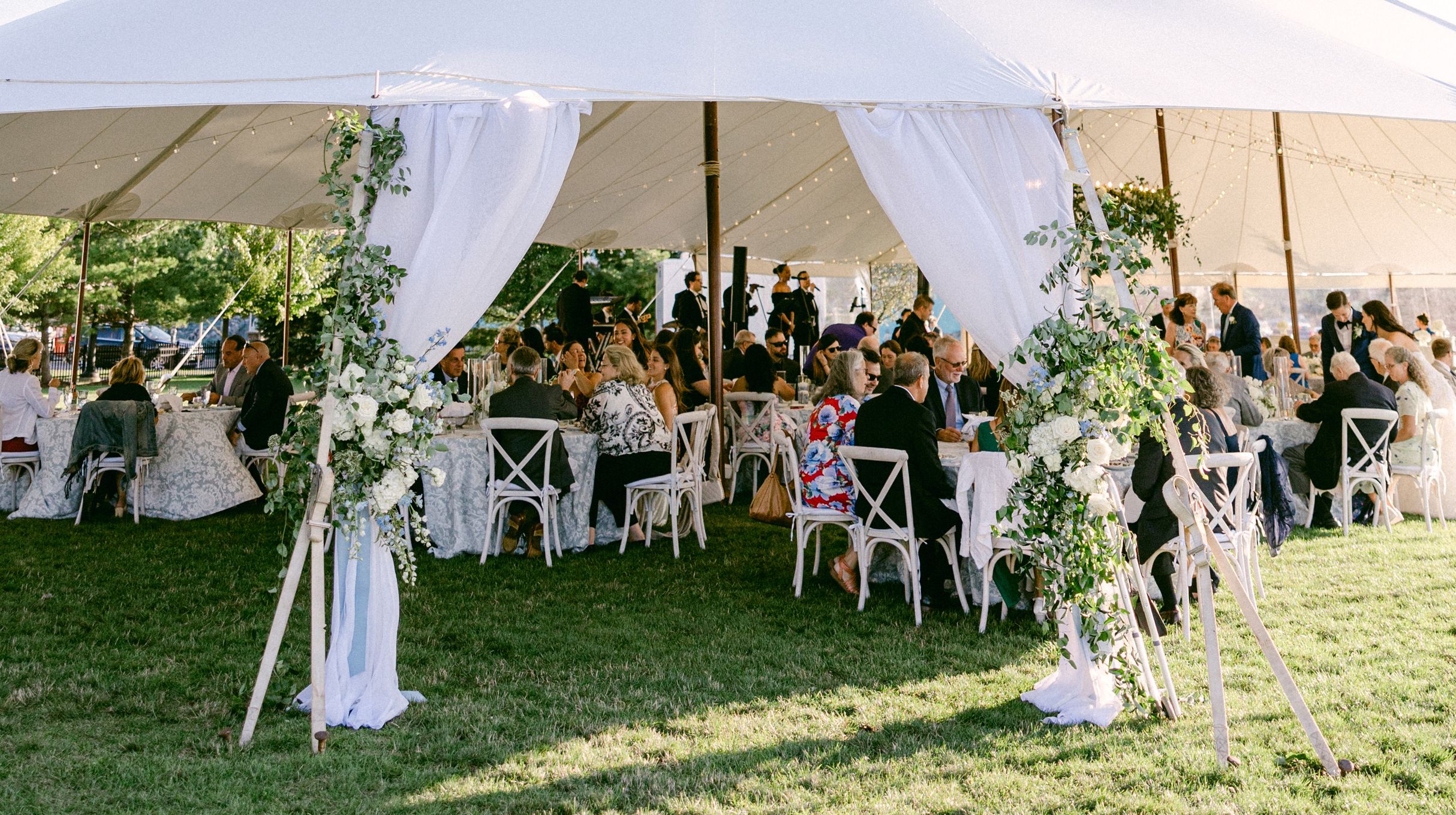 A wedding reception underneath a large white tent on the front lawn of the 1000 Islands Harbor Hotel