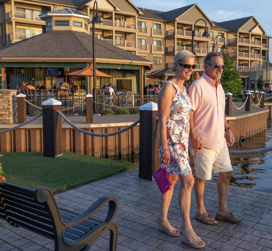 A couple walks along the bridge connecting the Carousel Bar to the island