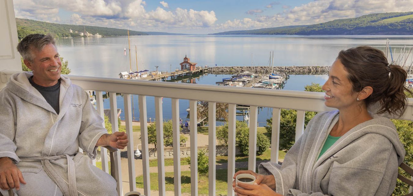 A couple in lush bathrobes enjoying breakfast on their balcony overlooking the lake