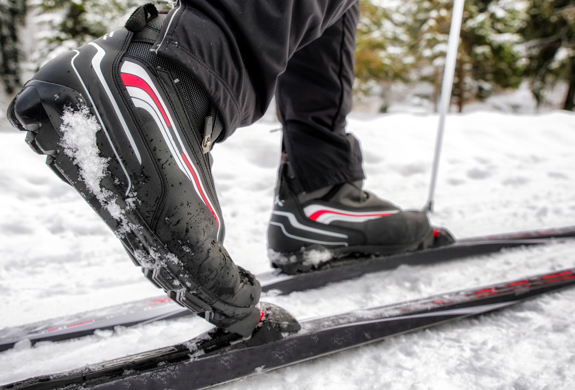 A close up on the boots of a cross country skier as they are mid-stride